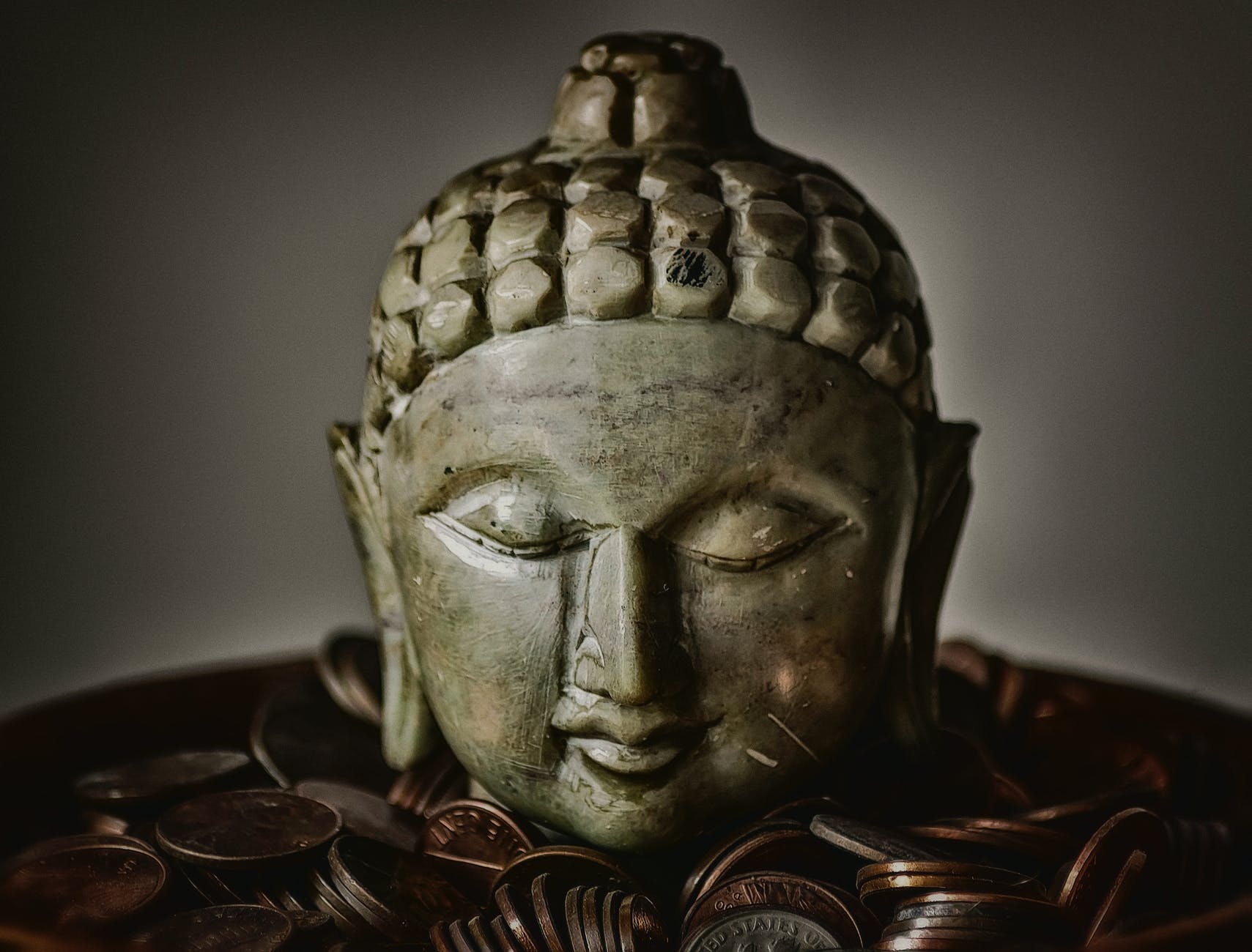 gautama buddha bust surrounded by coins